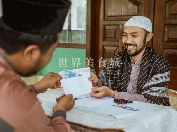 身穿傳統服飾的穆斯林把放著印尼盾鈔票的信封袋捐獻出去